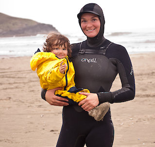 Child and mother in wet suit on a beach near Tofino